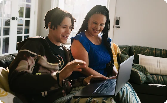 Mother and her son working together with their laptop at home